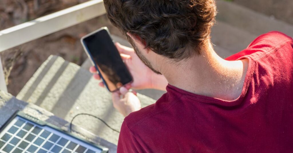 Mand oplader sin smartphone med en solcelle oplader